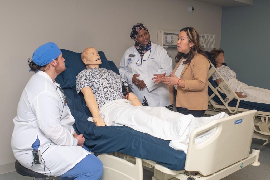 A group of health students discuss treatment for a patient dummy in the Simulation Lab