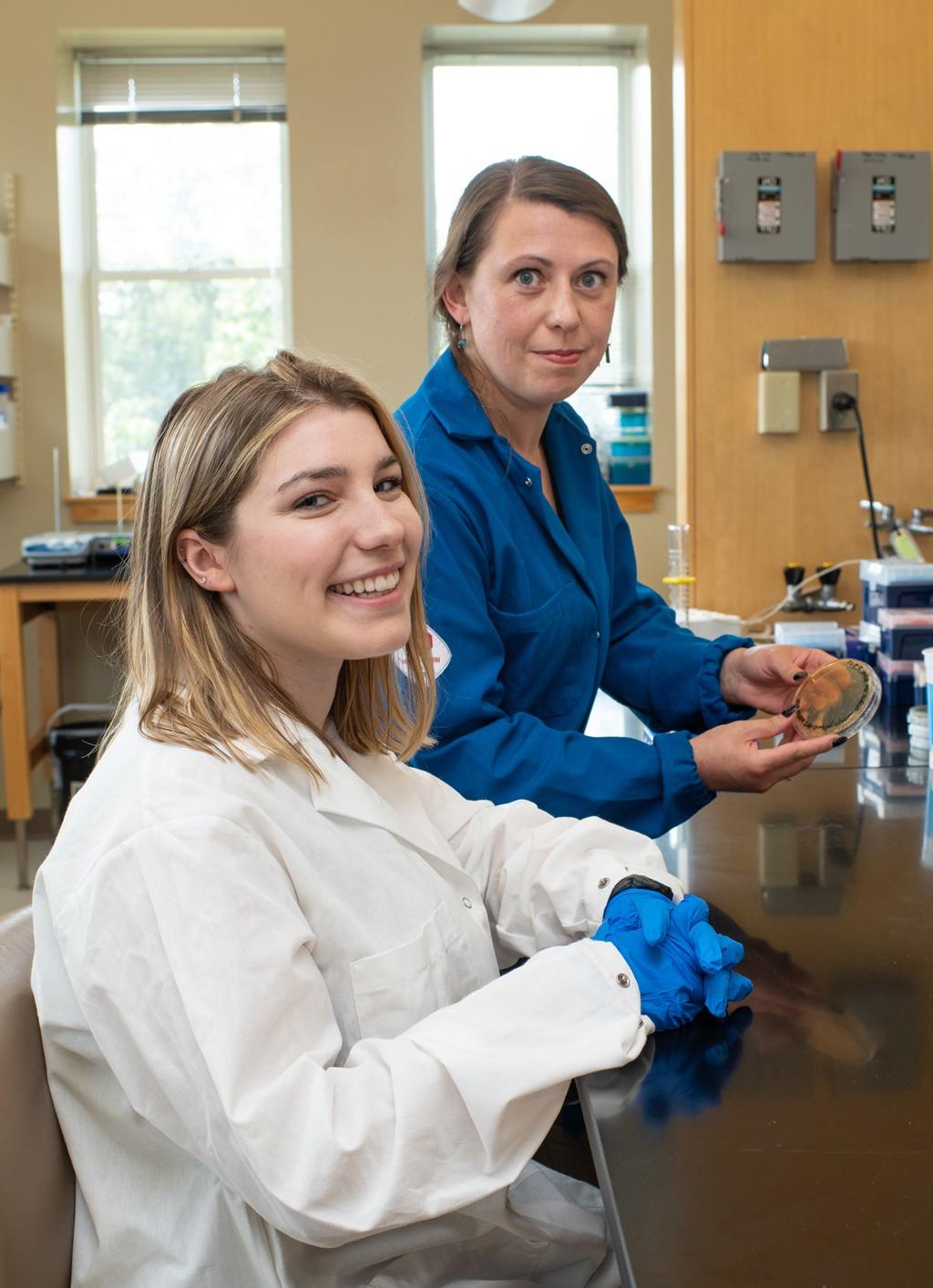 Professor Balog holds up an agar plate while standing next to a student researcher