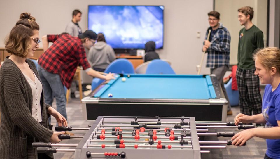 A group of students playing pool and foosball in the Commons