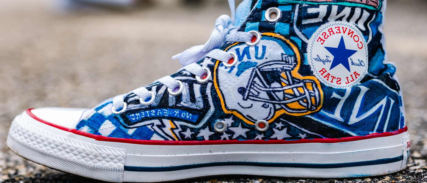 A Converse shoe is decked out in UNE logos and drawings