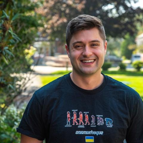 罗伯特·莫特利在欧洲杯外围盘口帕克馆外的院子里摆姿势拍照. He wears a shirt that reads "Superhumans," which is the name of the clinic he volunteered at in Ukraine.